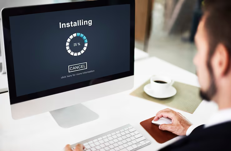 Man viewing software installation progress on computer screen in office setting with coffee cup nearby