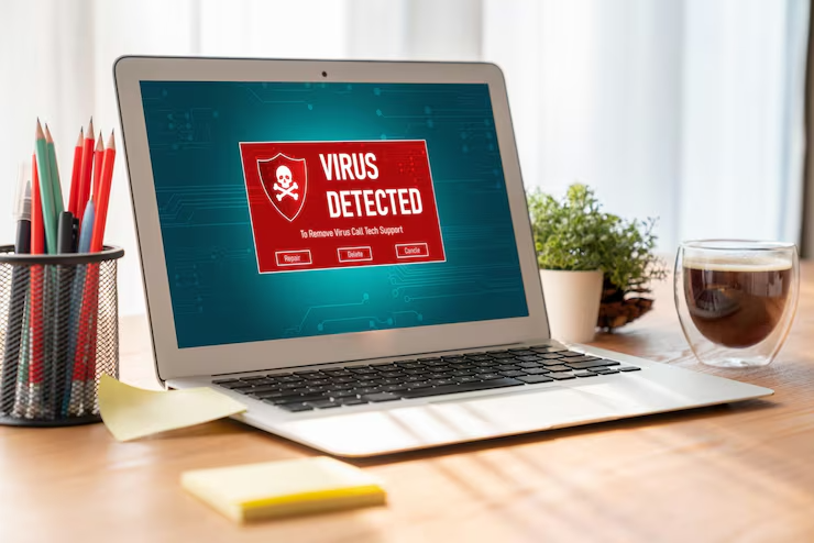 Alert on laptop screen showing virus detected warning with options to remove virus, coffee cup and plant in background
